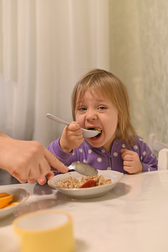 the little girl eats with great appetite. a big spoon in her hands. vertically