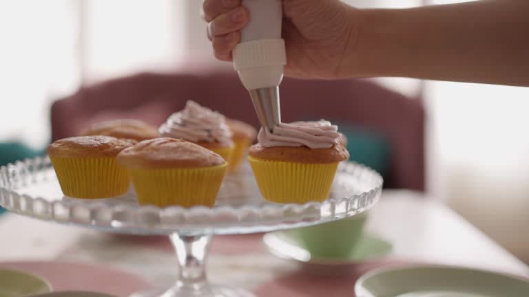 Woman adding cream on cupcakes