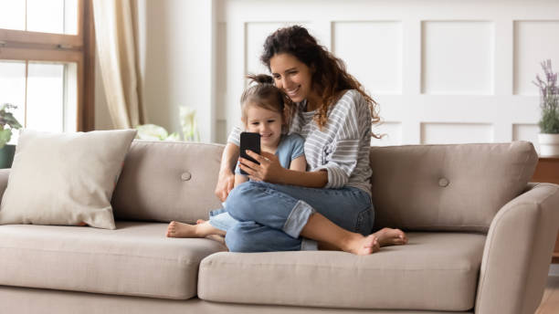istock Smiling young mom using smartphone with little daughter 1744506129
