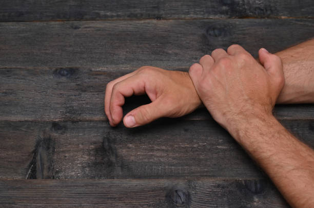 man's hands resting on wooden table. Close-up