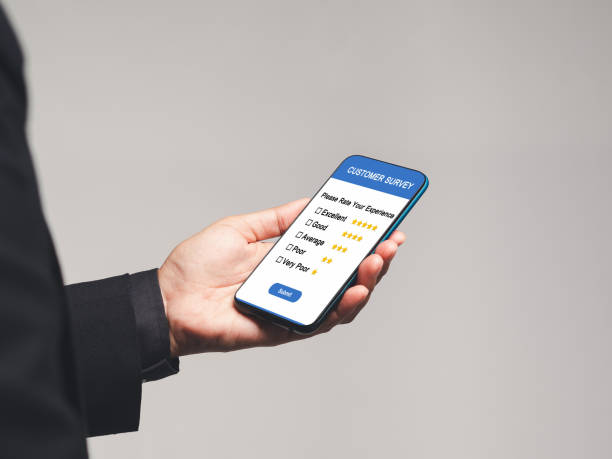 istock Businessman holding a smartphone with a customer survey form while standing on a gray background 1744506170