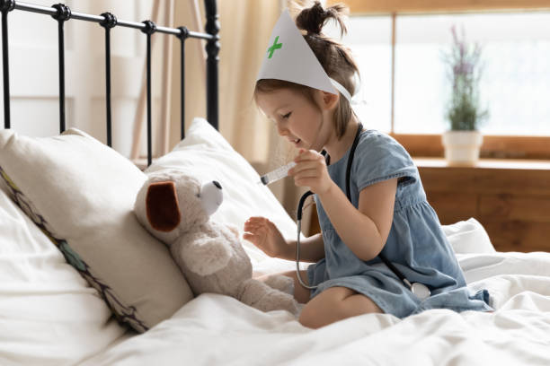 niña cariñosa jugando al médico con el oso de peluche - bed hospital prognosis patient fotografías e imágenes de stock