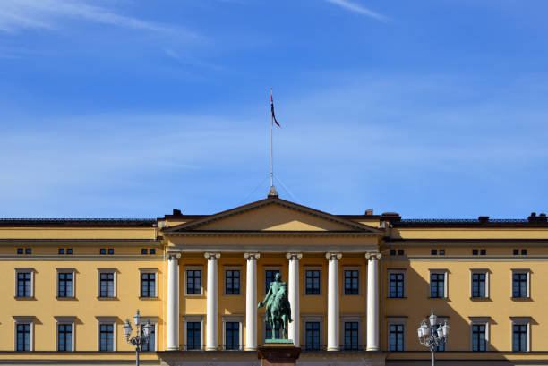 The King is in, the Royal's flag is flying over their mansion. Two Guards are visible in their guard kiosks, there are many more around the building, the grounds of which are open to the general public.