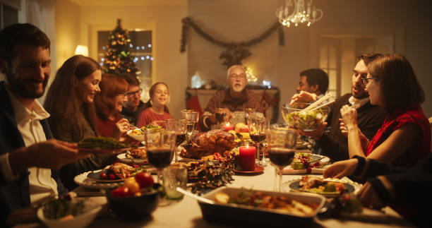 портрет женщины, обедающей вместе за большим столом с членами семьи. близкие разговаривают, смеются и наслаждаются вкусной едой. уютный ужи - having ones say стоковые фото и изображения