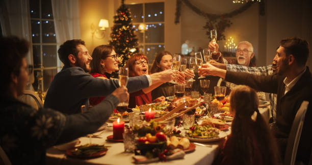 retrato de un apuesto joven negro proponiendo un brindis en una mesa de la cena de navidad. familiares y amigos compartiendo comidas, levantando copas con champán, brindando, celebrando unas vacaciones de invierno - navidad fotografías e imágenes de stock