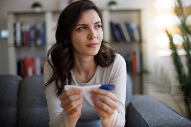 Thoughtful young woman waiting for pregnancy test result stock photo