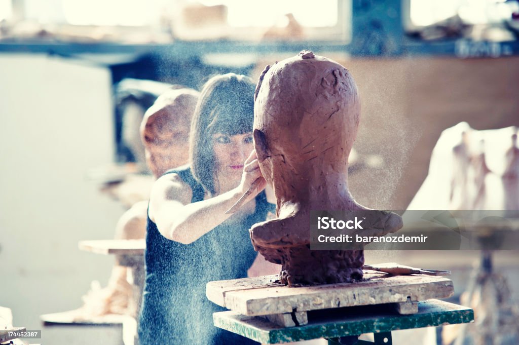 Creating Sculpture Beautiful young sculptor creates a clay sculpture Art Stock Photo