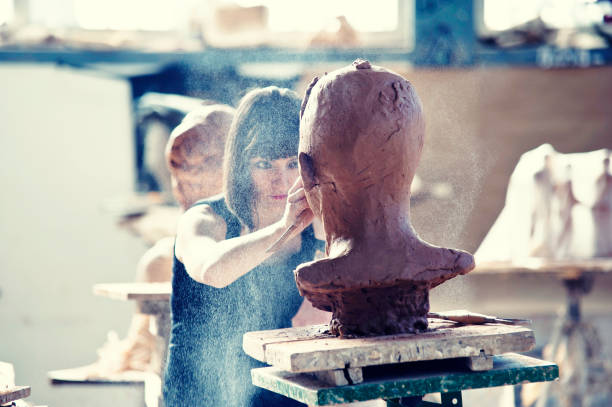 Creating Sculpture Beautiful young sculptor creates a clay sculpture clay sculpture stock pictures, royalty-free photos & images