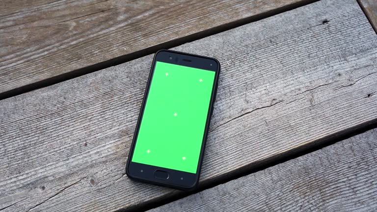 a smartphone with a green screen lies on a faded wooden background