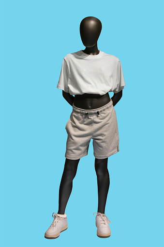 Full length image of a child display mannequin wearing white t-shirt and gray shorts isolated on blue background
