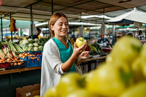Young beautiful happy female nurse buying vegetables