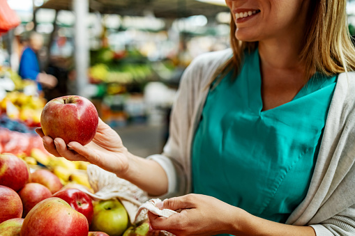 Happy female nurse buying fresh apples