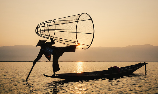 Inle Lake, Myanmar - Feb 16, 2016. Local man using the unique methods of rowing and catching fish on Inle Lake (Shan State).