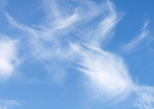 A random pattern of wispy cirrus clouds in a soft blue sky on a sunny day.