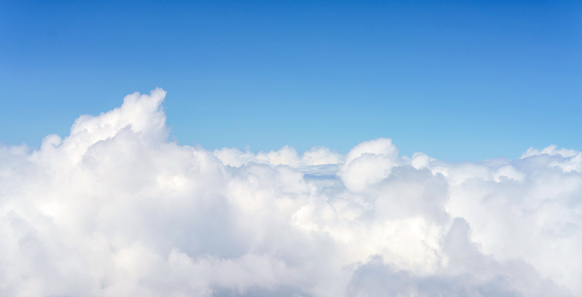 An aerial view of bright, fluffy clouds above a clear blue sky.