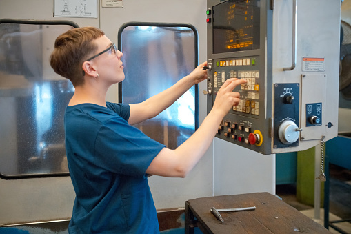 Female engineer examining machinery in factory