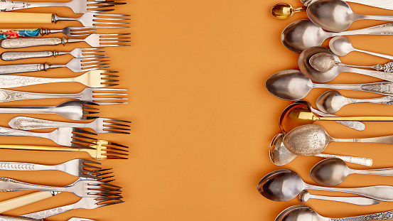 Cutlery. Flat lay photo of variety of antique silverware and gold kitchen forks and spoons arranged against studio background. Concept of food, holiday, table setting, retro, vintage. copy space