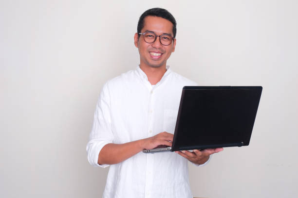 istock Adult Asian man smiling confident while holding a laptop 1744638567