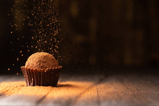 istock Delicious chocolate truffles sprinkled with cocoa on a black reflective background. 1744644813