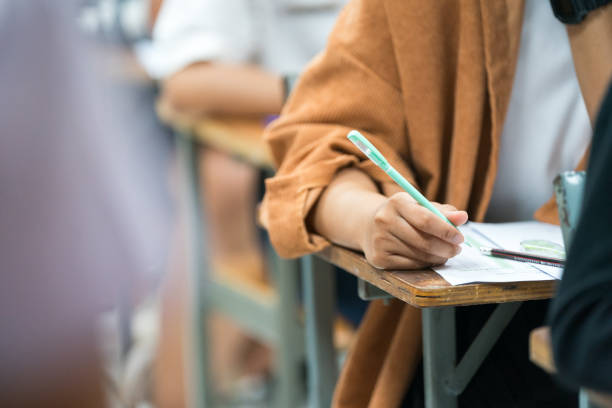 istock Selective focus high school or university students concentrate writing on paper answer sheet for final exam in the classroom 1744707520