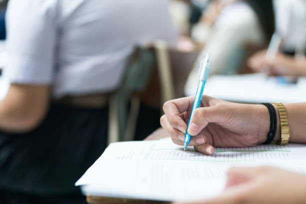 istock Selective focus high school or university students concentrate writing on paper answer sheet for final exam in the classroom 1744707553