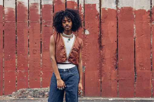 Young black man in New York posing against a red wall.