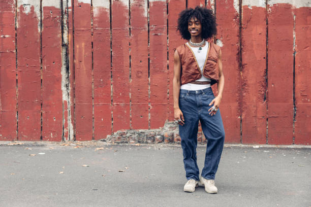 Young black man in New York posing against a red wall.