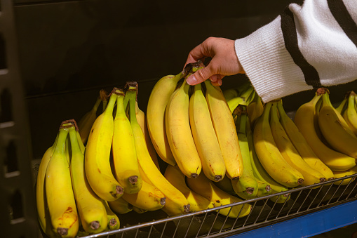 hand taking bananas from grocery store shelf copy space