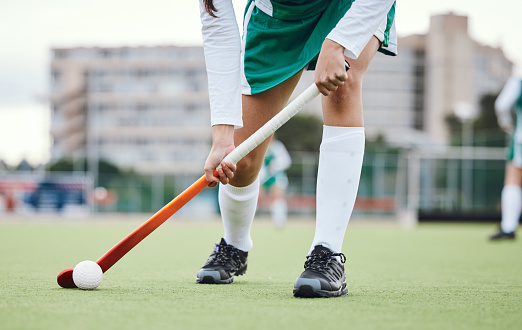 Fitness, legs and hockey stick with a sports person on a court or field during a game for competition. Exercise, grass and ball with a player training at practice on astro turf for health or wellness