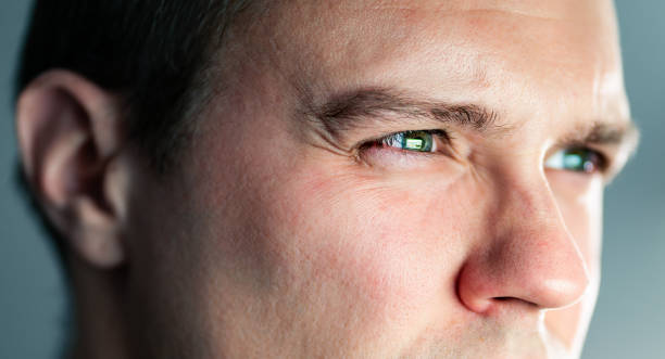 istock Squinting eyes of a man looking at screen. Poor eyesight, bad vision. Light from laptop computer or phone. Guy watching tv. Focus on work. Closeup of face. Nearsightedness or myopia. 1744768963