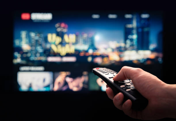 Watching movie stream service on tv. Video on demand subscription service and platform in television. Streaming series, films and shows online. Man using remote control. stock photo