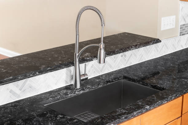 istock A kitchen faucet detail with a black marble countertop and herringbone backsplash. 1744782242