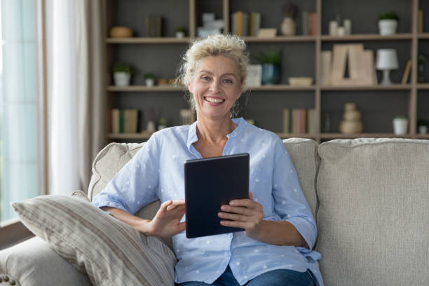 istock Happy pretty mature retired woman holding digital tablet computer 1744783412