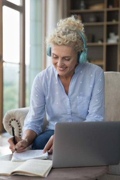 istock Positive engaged older student lady in big headphones writing notes 1744783435