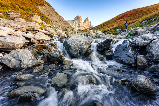 Dramatic landscape of iconic three peak mountain and waterfall flowing in the valley of Aiguilles dArves in French alps on autumn at Savoie, France