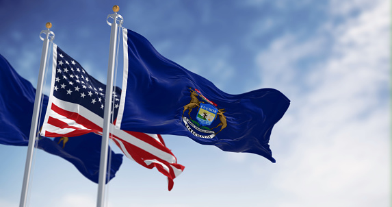 Two flags of the state of Michigan waving in the wind with the national flag of the United States. 3d illustration render. Rippling fabric