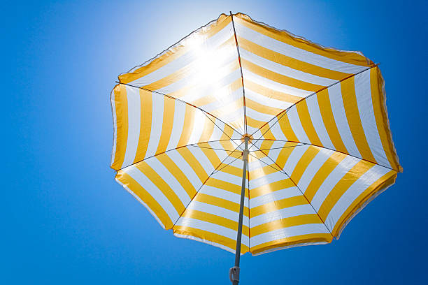 giallo ombrello contro il sole e cielo blu - parasol umbrella sun beach foto e immagini stock