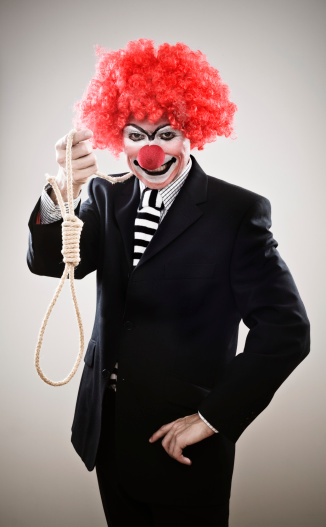 A businessman dressed up as clown holding a noose and grinning.