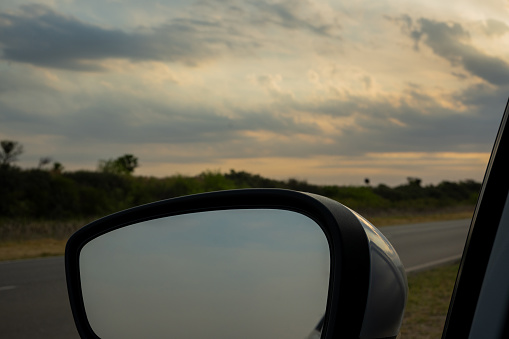 Rearview mirror of a car, which is parked on the side of the road.