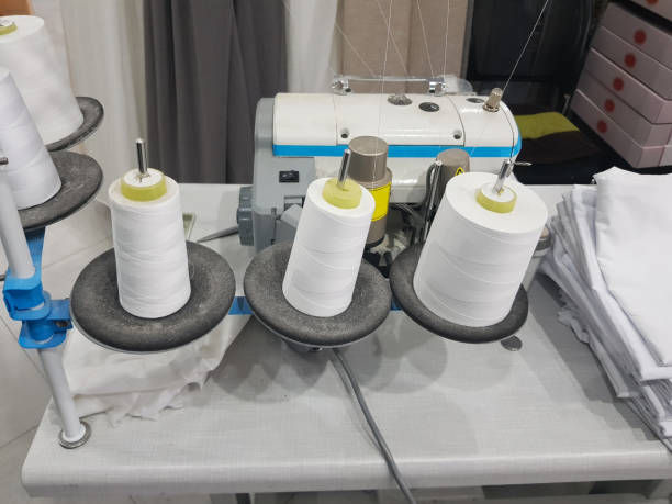 istock Workshop with overlock sewing machine and thread. Sewing factory manufacture craft business 1744808410