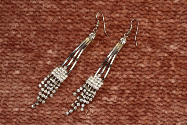 istock Silver handmade earrings on tinsel on brown textured fabric background 1744817866