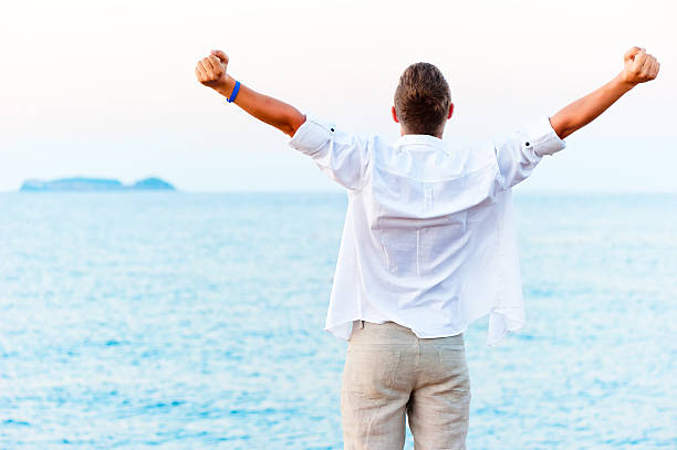 istock man with hands raised at the beach 174481897
