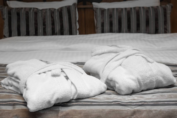 istock Two folded white bathrobes on the bed. Comfortable bed ready for sleep and rest. 1744829318