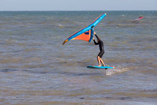 Wind surfer with red blue sail on beach of Canary Islands starts his turn