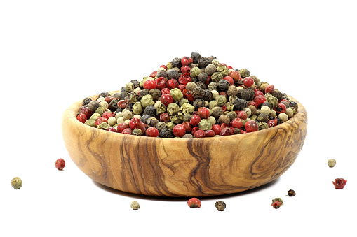 mixed peppercorns in a bowl made of olive wood  isolated on white background