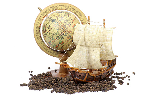 black peppercorns with globe and sailing ship isolated on white background