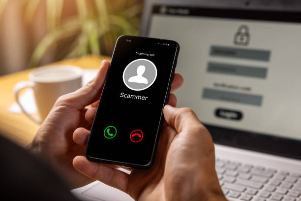 phishing - hands holding phone with incoming call from scammer stock photo