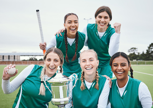 Women, hockey team and winning trophy in portrait, celebration and success in competition on field. Champion girl group, friends and diversity for sports, goal or happy outdoor at stadium for contest