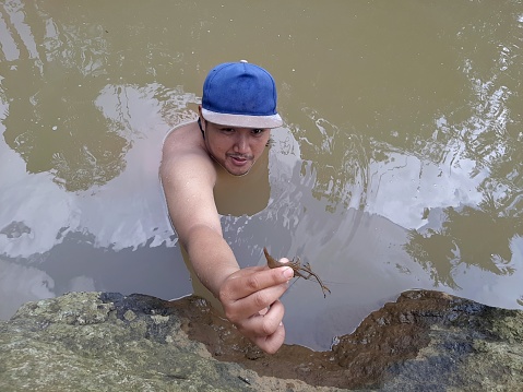 A young boy swims in the river and catches shrimp