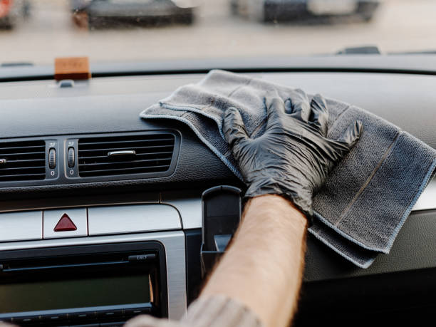 istock Man's hand in black glove cleaning car interior, dashboard and leather seats with microfiber cloth. Hand wipe down suede leather seat saloon interior. 1744855162